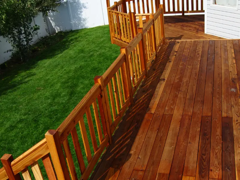 Multi-level wood deck with guard rail connecting upper and lower sections.