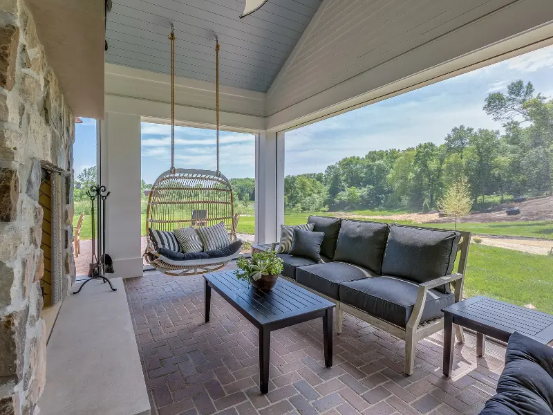 Covered patio with a vaulted white ceiling and screened openings over a brick paver floor.