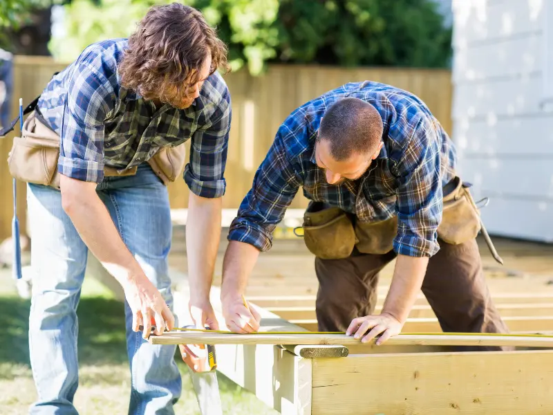 Deck builders measuring and marking decking boards.