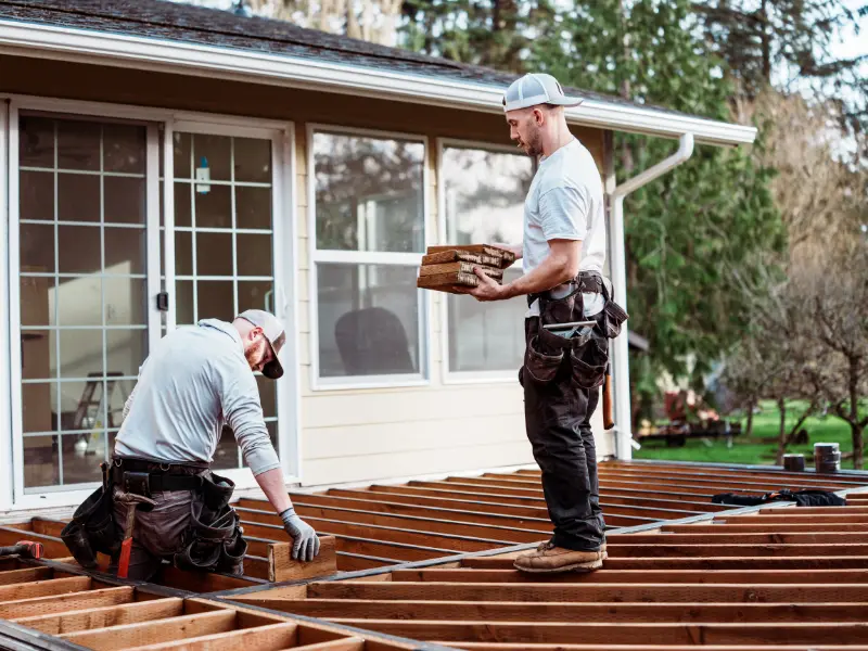 Deck builders framing joists for a new backyard deck.