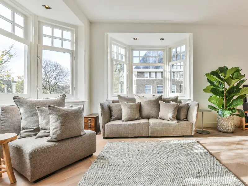 Sunroom-style living room with large windows and neutral seating