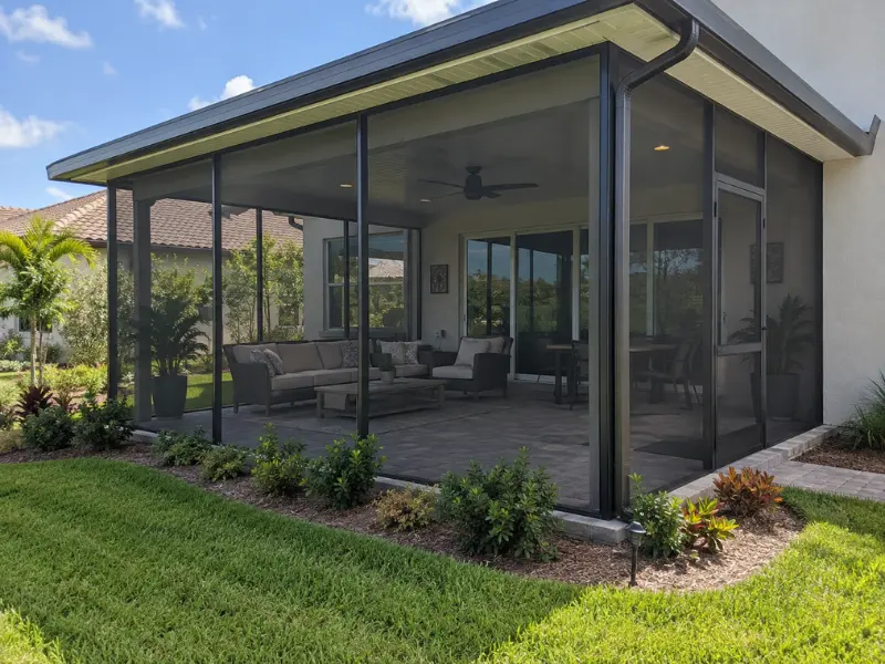 Custom screen enclosure with gable roof covering a backyard patio with outdoor seating and ceiling fan. Custom screen enclosure with gable roof covering a backyard patio with outdoor seating and ceiling fan.