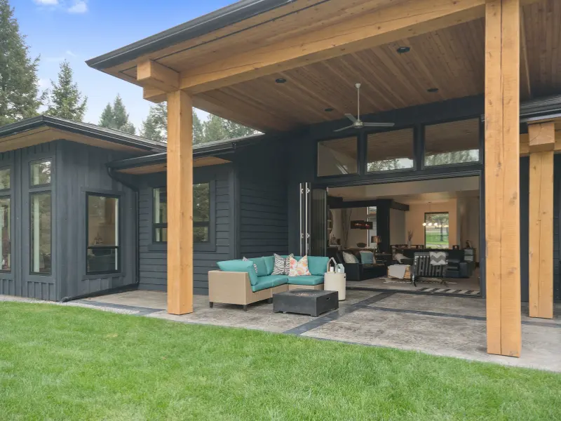 Solid patio cover with wood beams and a tongue-and-groove ceiling over a teal outdoor sectional, connecting the patio to the open living room. Solid patio cover with wood beams and a tongue-and-groove ceiling over a teal outdoor sectional, connecting the patio to the open living room.