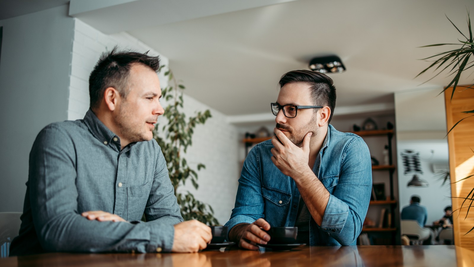Two people talking across a table, one listening closely