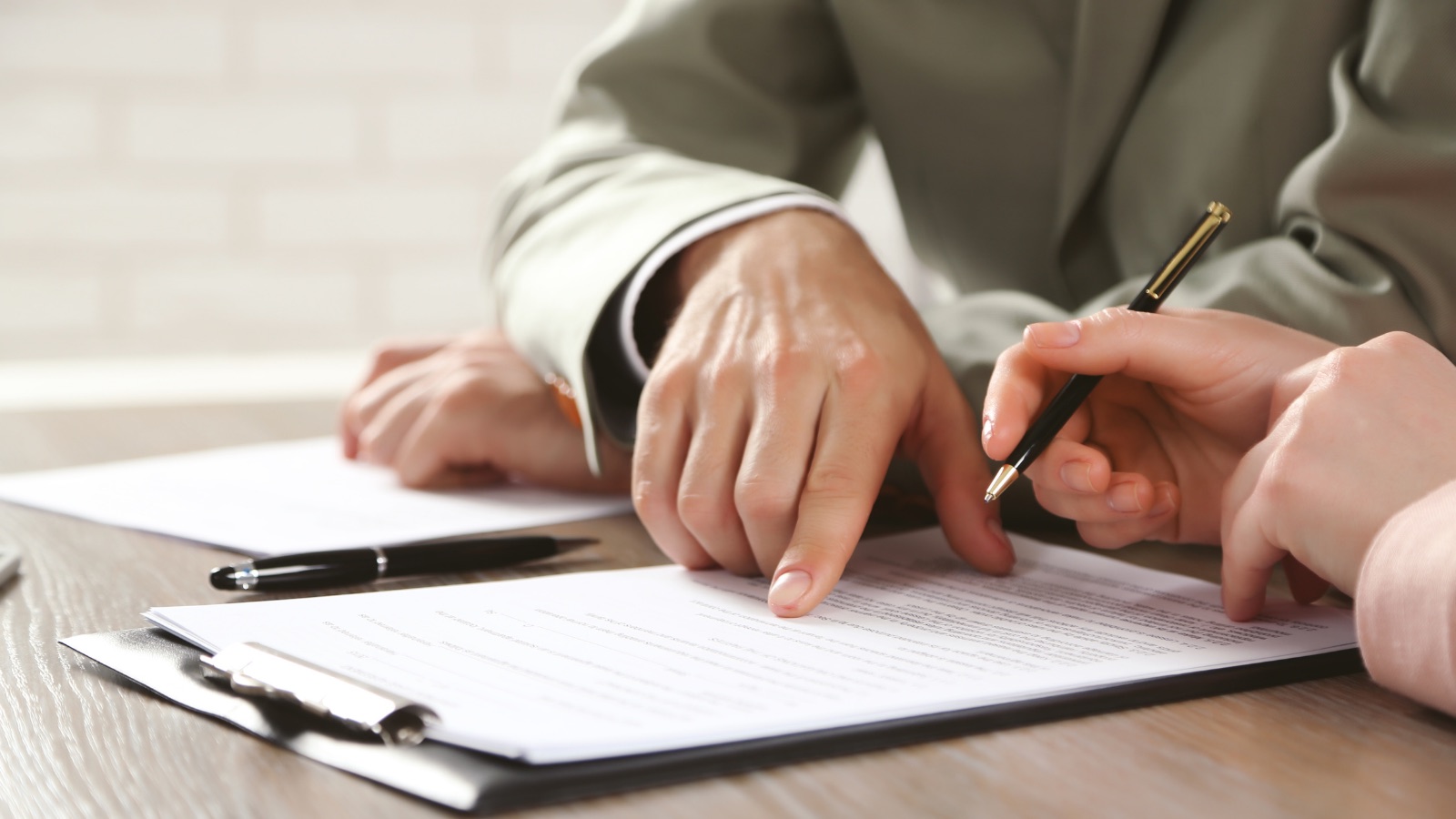 Two people at a table going over a printed form, one pointing to a line while the other holds a pen