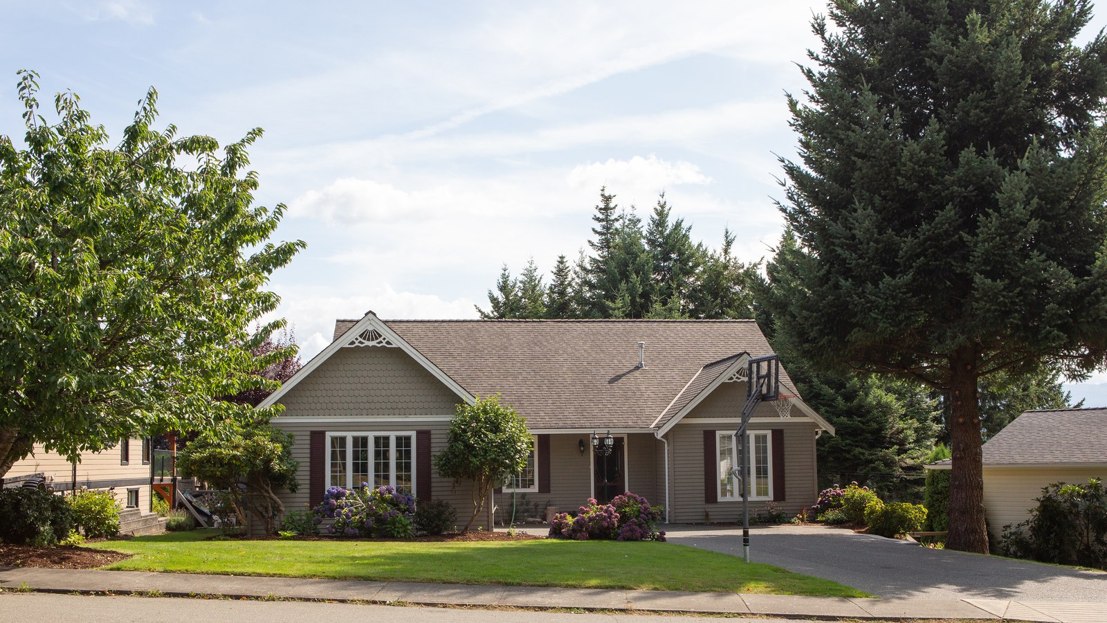 A single-story house with a green front lawn on a quiet residential street