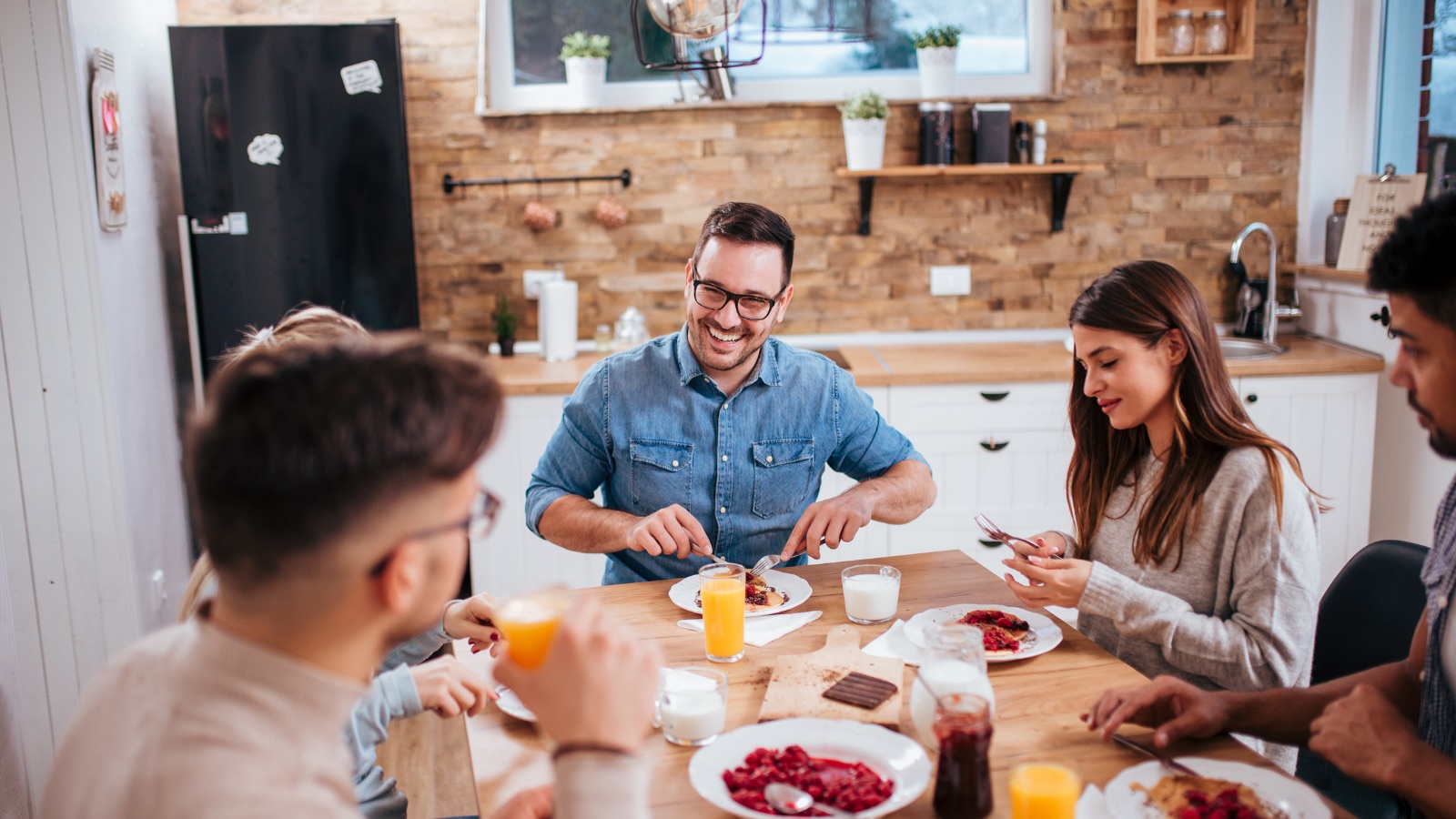 A group of friends talking over a meal around a kitchen table