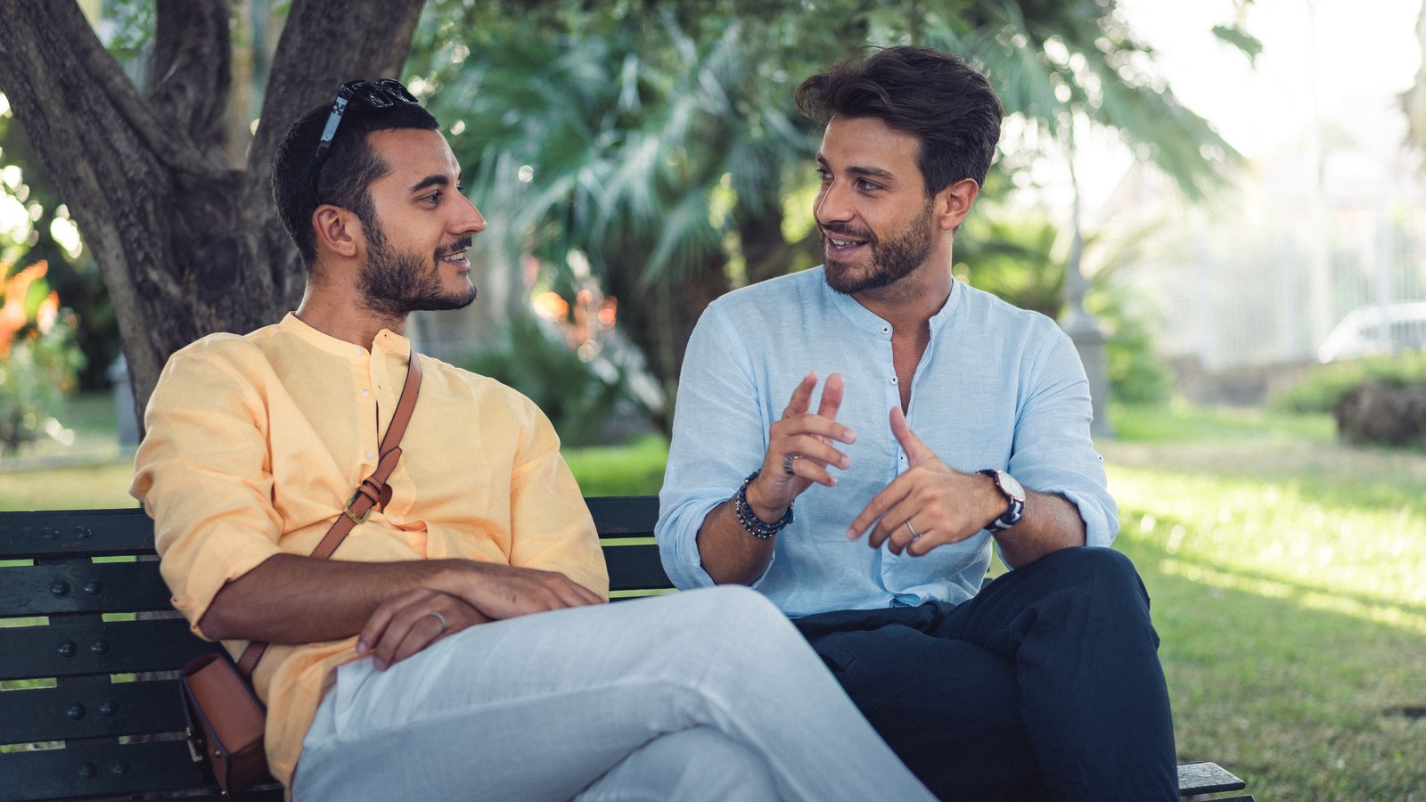 Two men sitting on a park bench in relaxed, engaged conversation