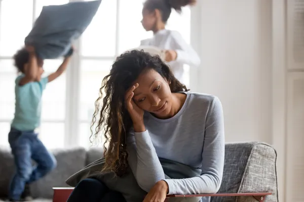 Stressed out mom with kids jumping on the couch