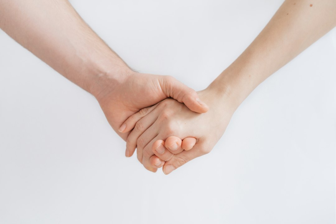 Two clasped hands, one larger and one smaller, against a plain white background.