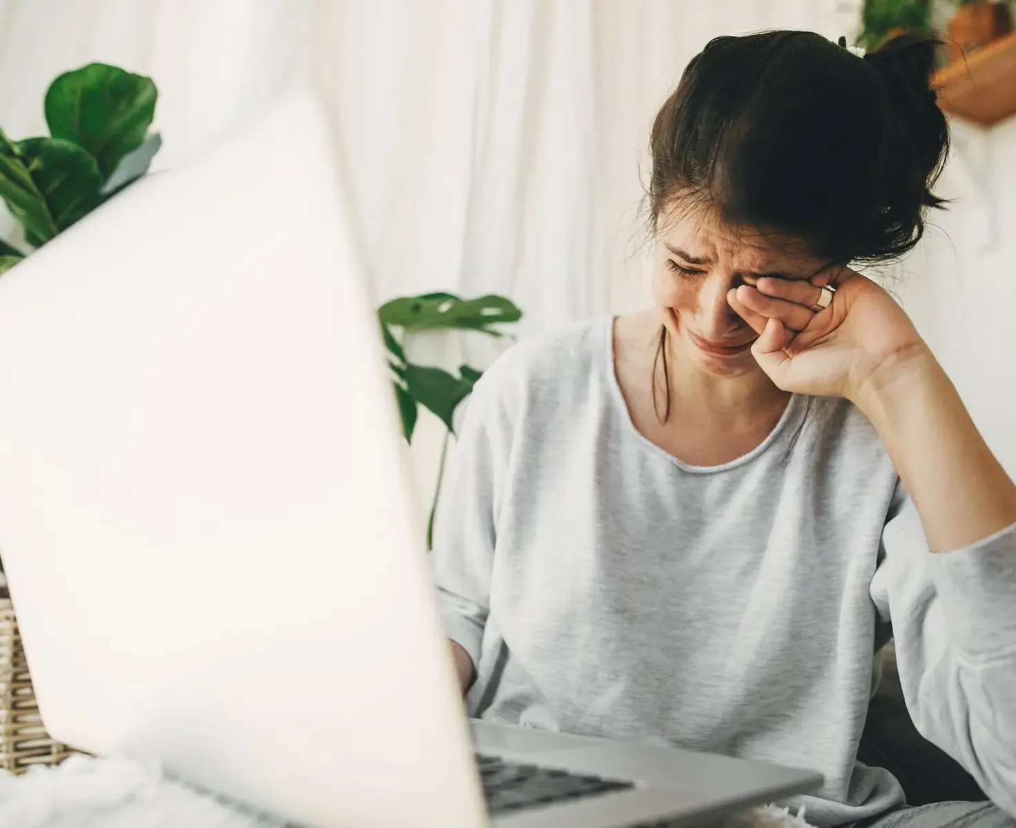 Woman sitting behind a laptop with tears on her face during an emotional moment