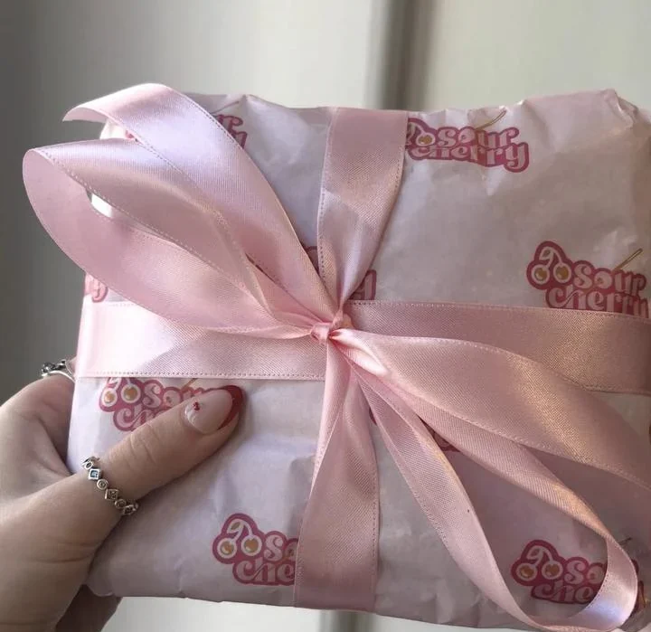 An order wrapped in pink Sour Cherry tissue paper tied with a ribbon