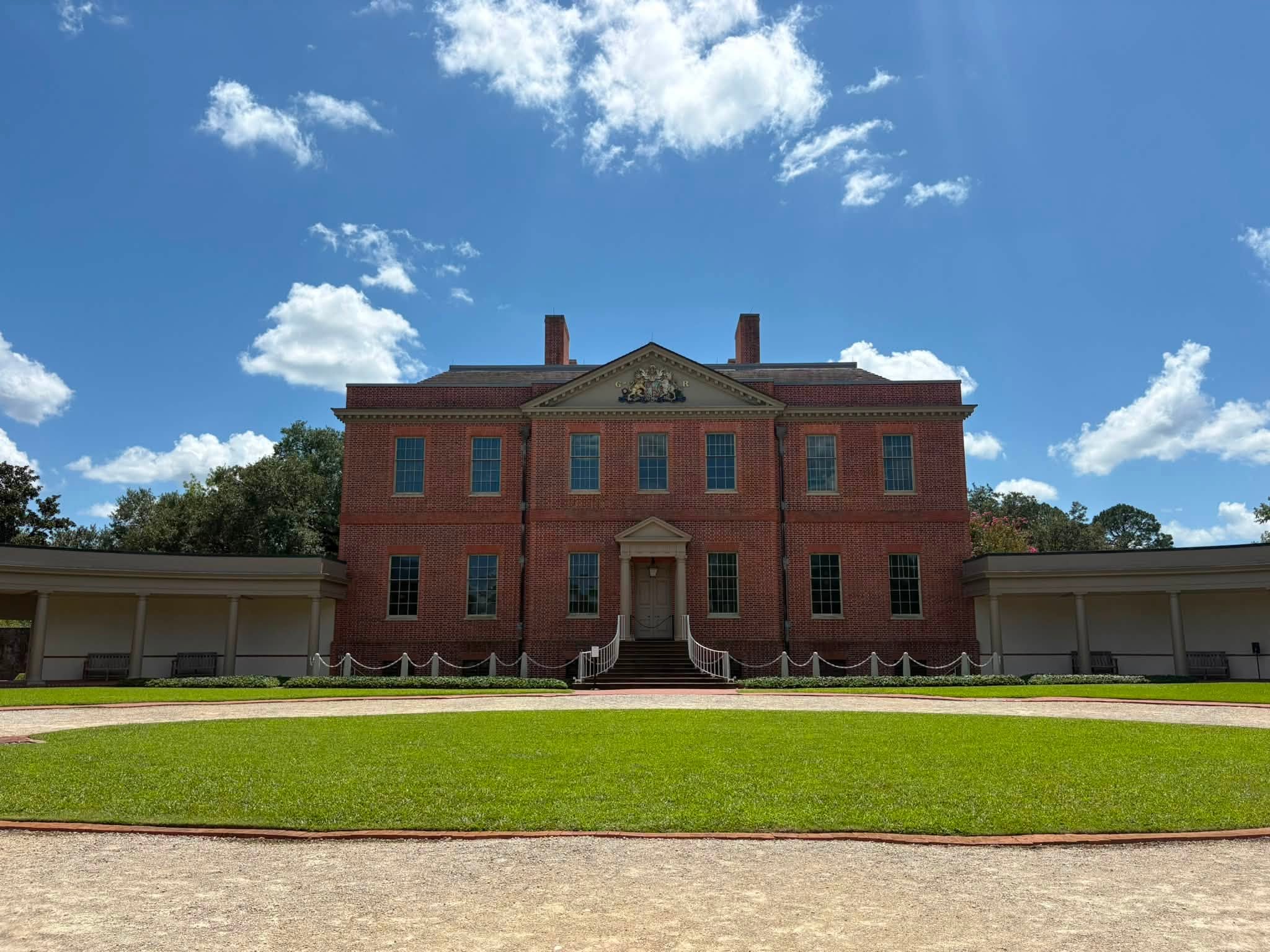 The red-brick Tryon Palace under a blue summer sky, with a lawn in front.