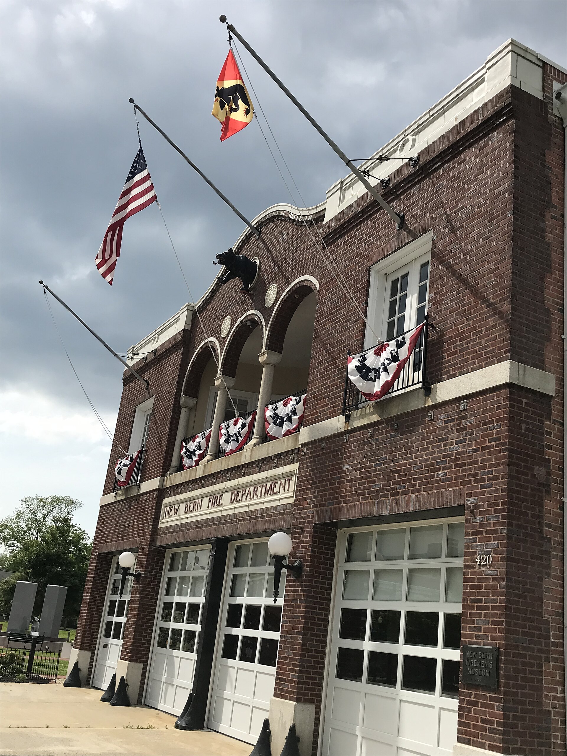 The brick front of the New Bern Firemen's Museum at 420 Broad Street, with flags and bunting.