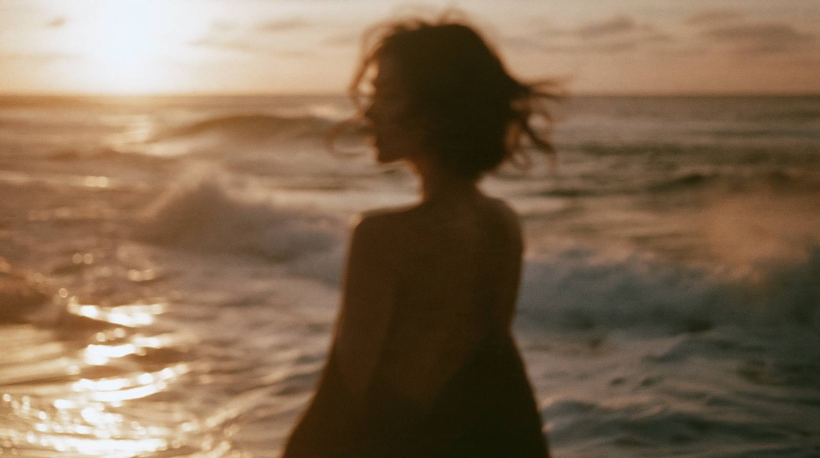 Woman facing the sea at sunset