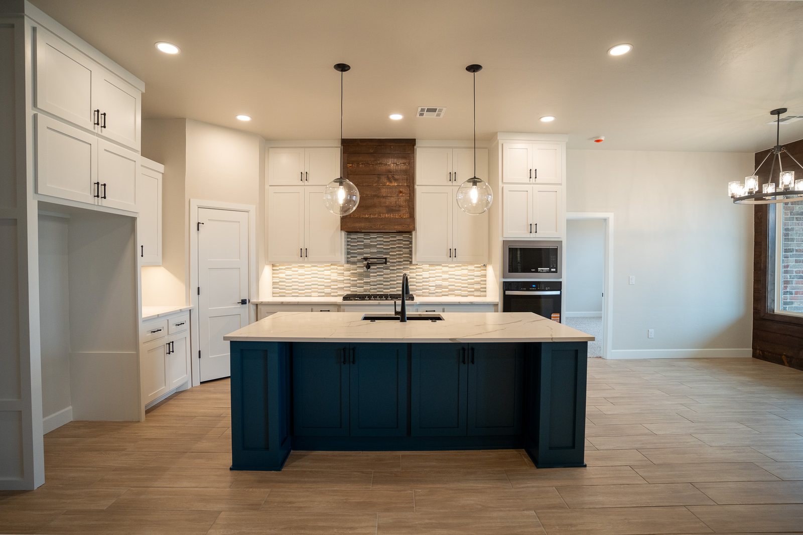 Clean kitchen with a navy island, white cabinets and quartz counters