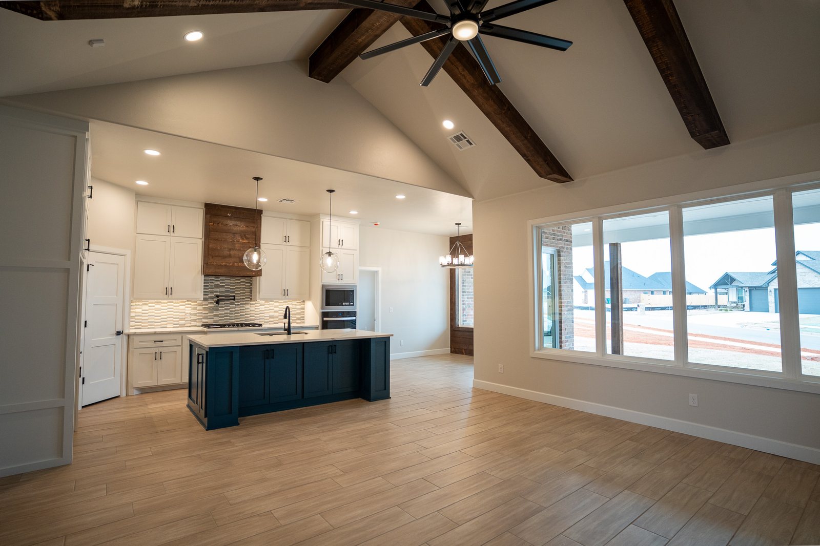 Open living room looking into the kitchen under wood beams