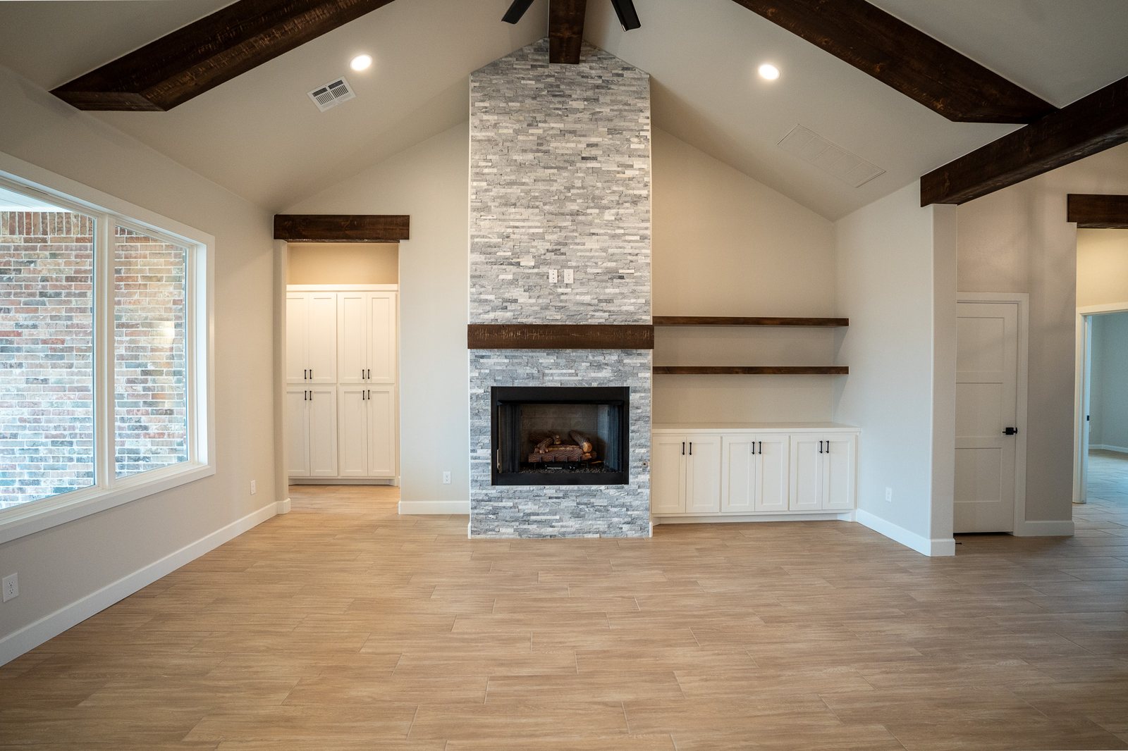 Living room with a stone fireplace and vaulted beamed ceiling