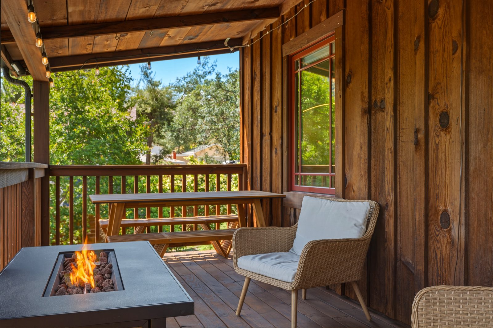Shaded covered deck with a fire table and picnic table among the trees