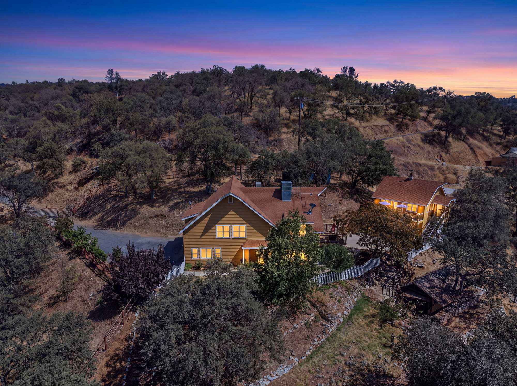 Aerial view at dusk of a two-story home among oak-covered foothills in Tulare County