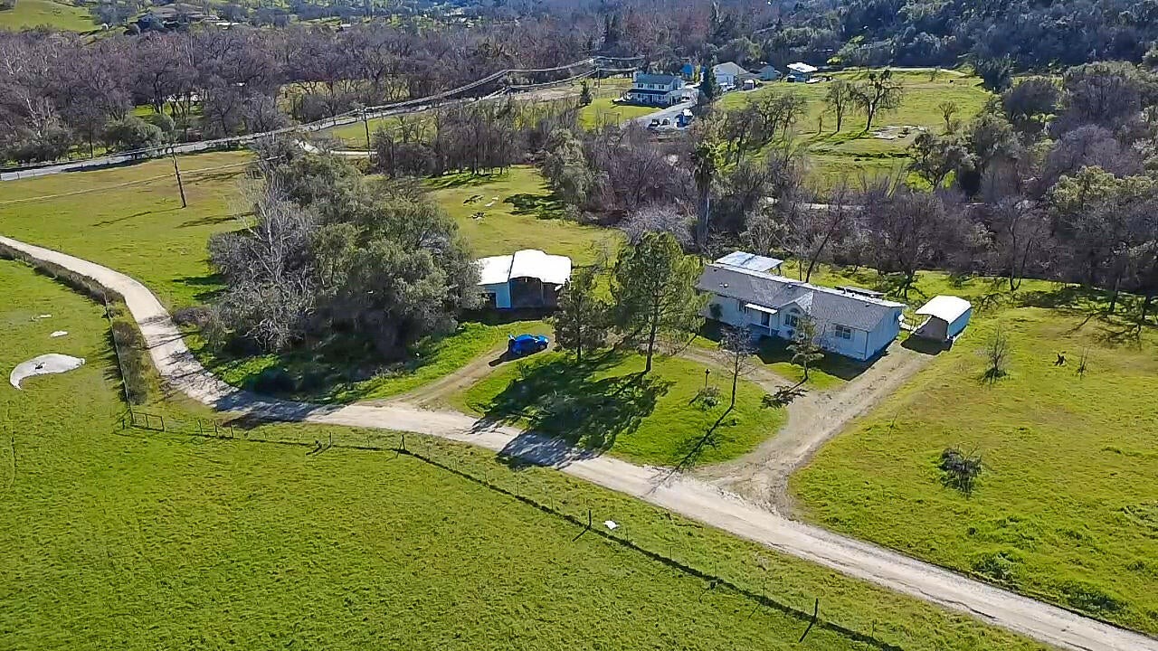 Aerial view of a foothill ranch with green pasture and a dirt drive in Tulare County