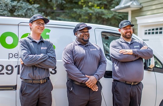 three proof. technicians smiling in front of a van