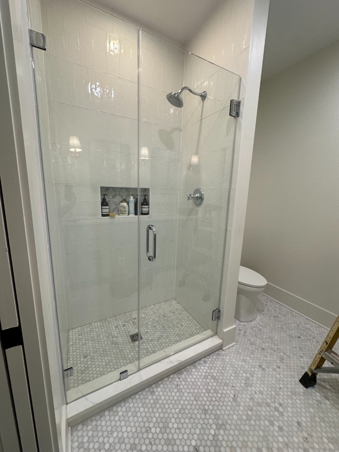 Close-up of polished chrome shower door handle on frameless glass