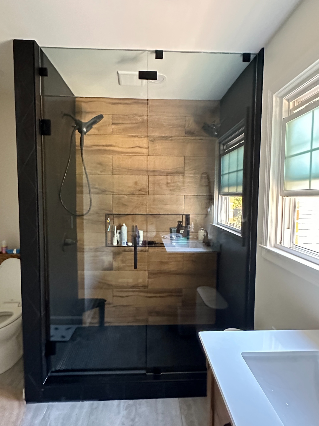 Frameless shower door with matte black hardware on marble tile
