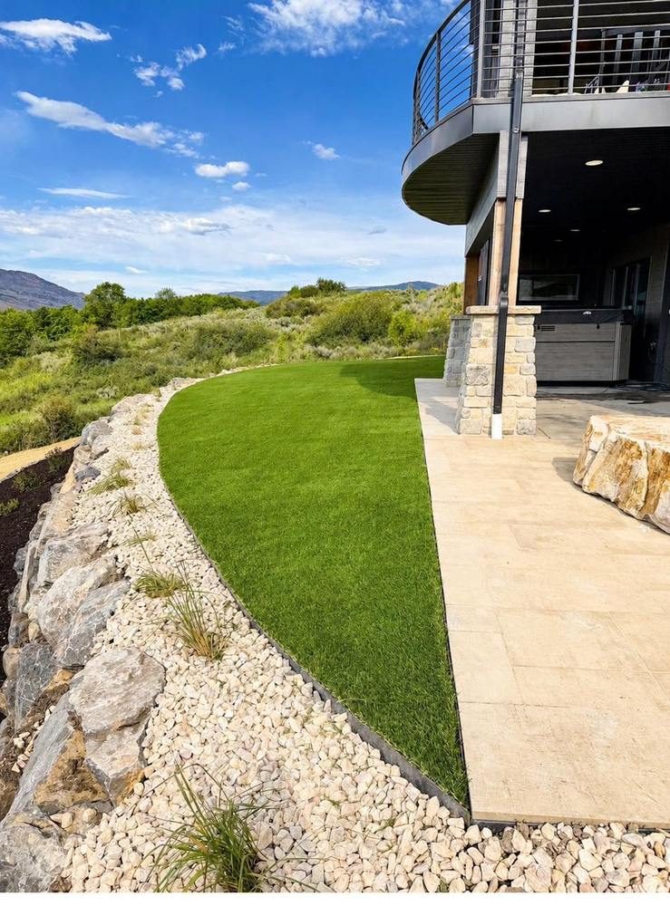 Curved artificial turf lawn beside a modern home with mountain views