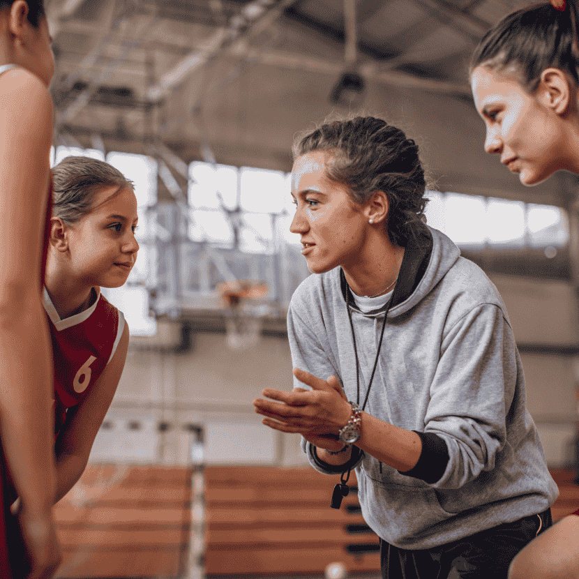 group of female athletes and sports coach in a huddle supported by their coaching symbolizing faith-integrated mental performance coaching services