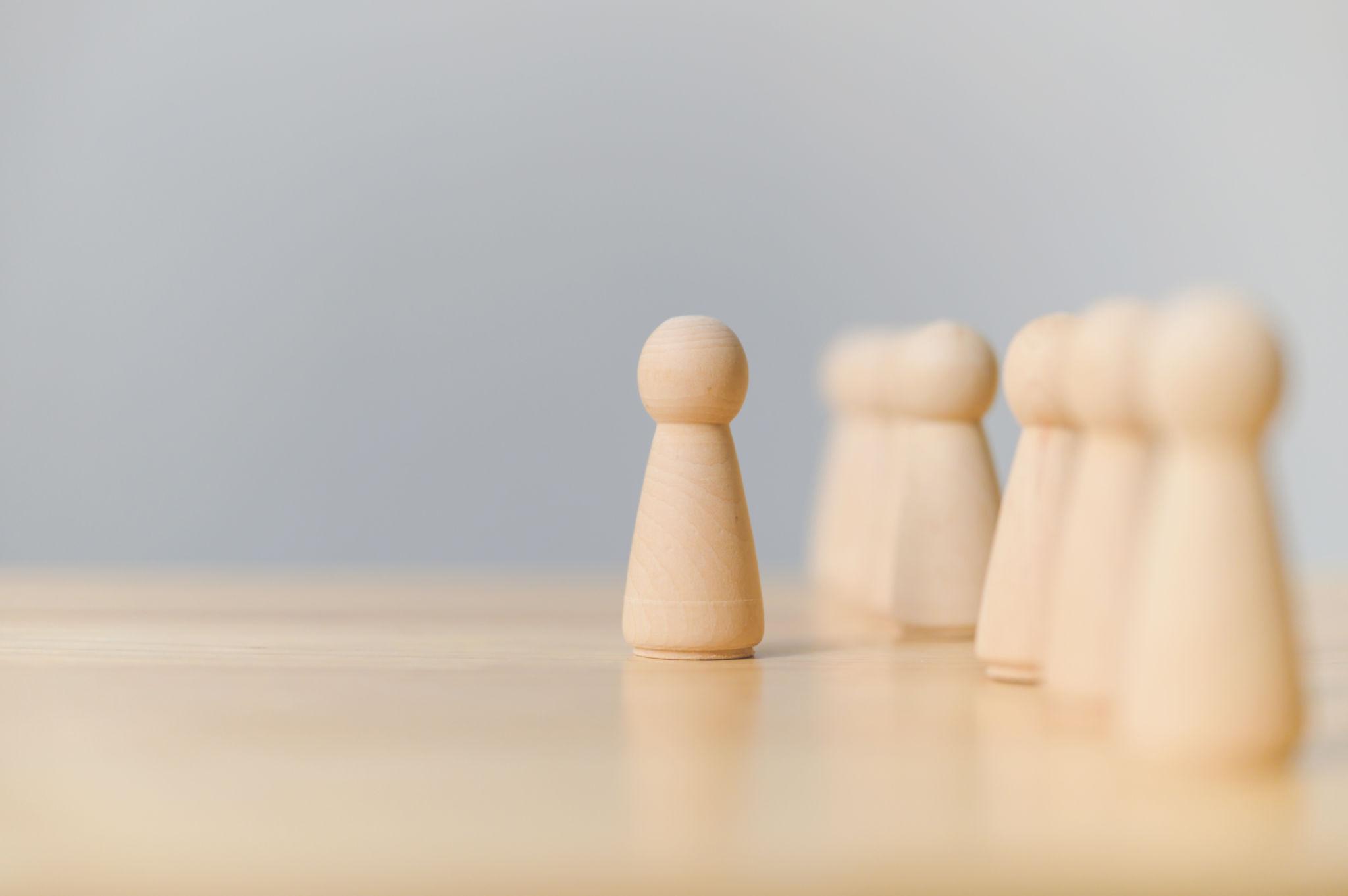 wooden figure standing apart leadership