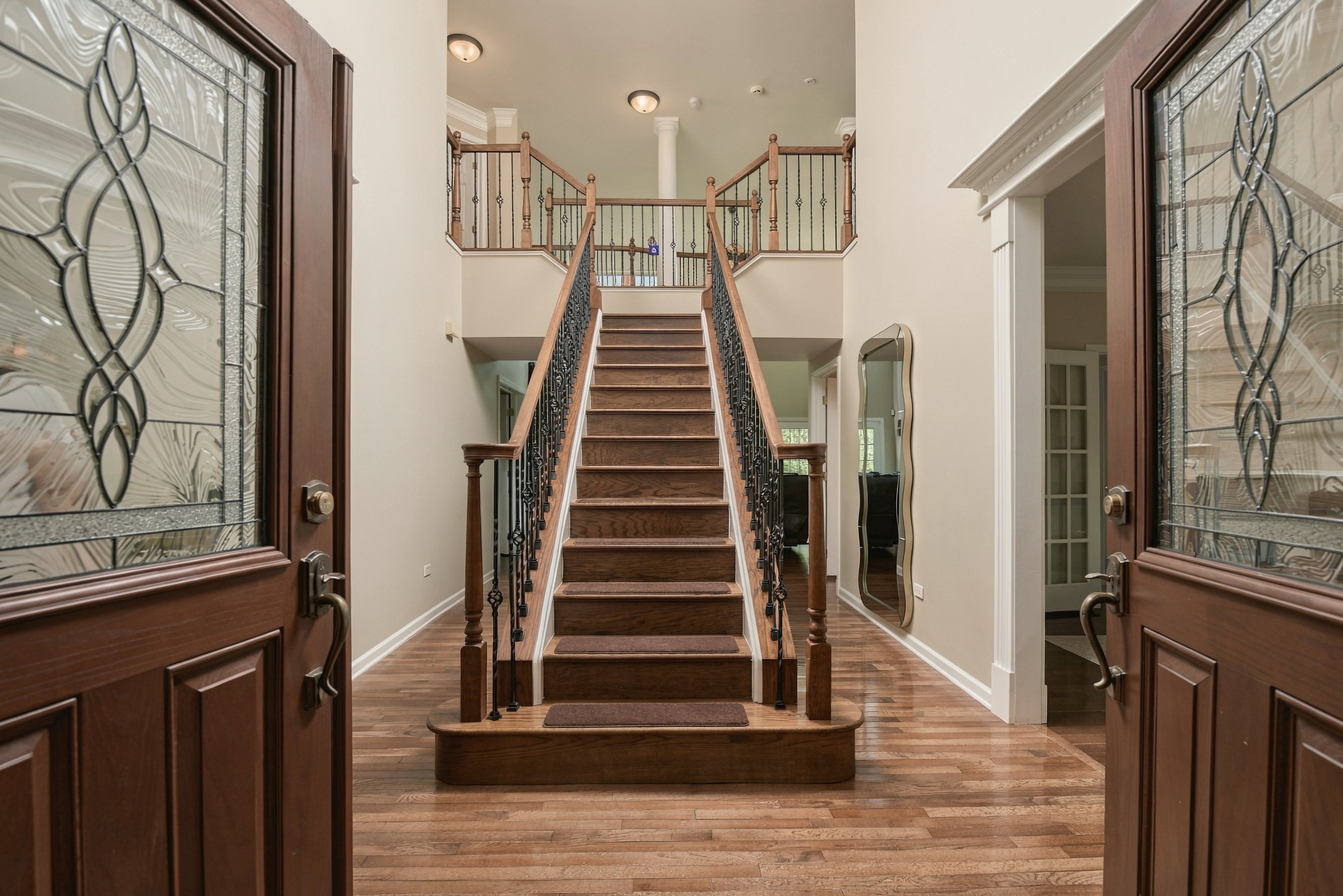 Architectural real estate photography featuring a grand staircase framed by decorative entry doors, photographed by Listing Ninjas Media