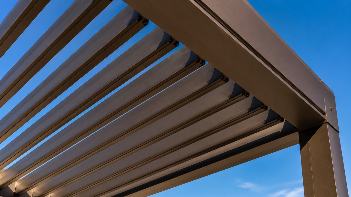 Close detail of aluminum pergola slats filtering sunlight against a blue Arizona sky