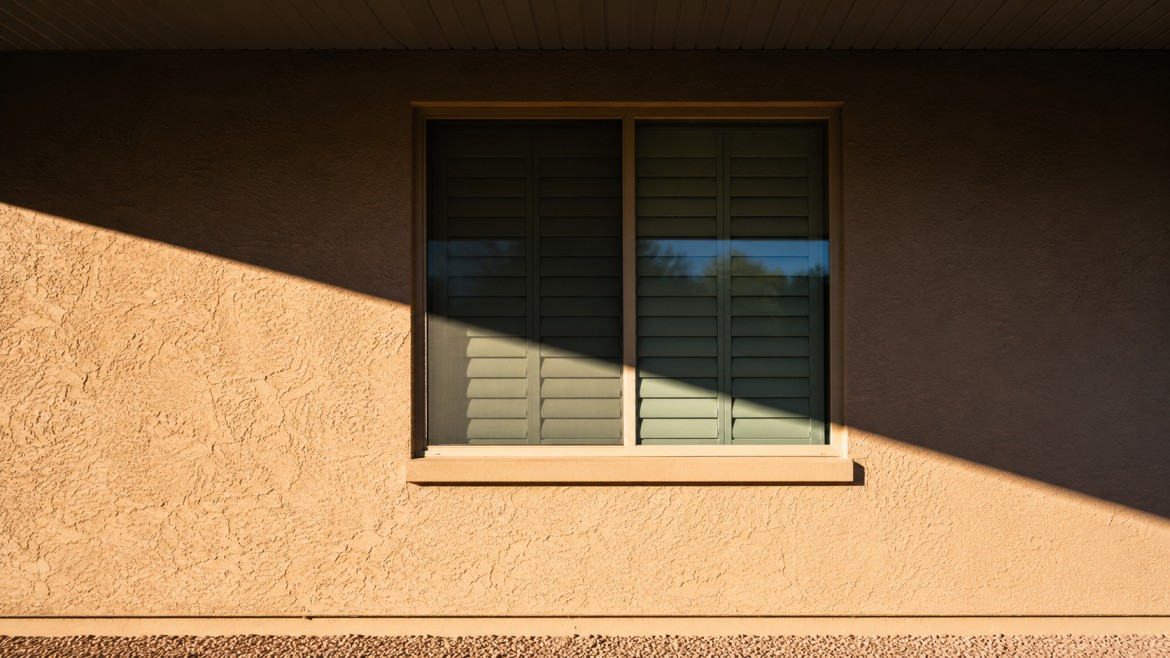 Shade line across a stucco wall showing shaded and sun-exposed sections of an Arizona home