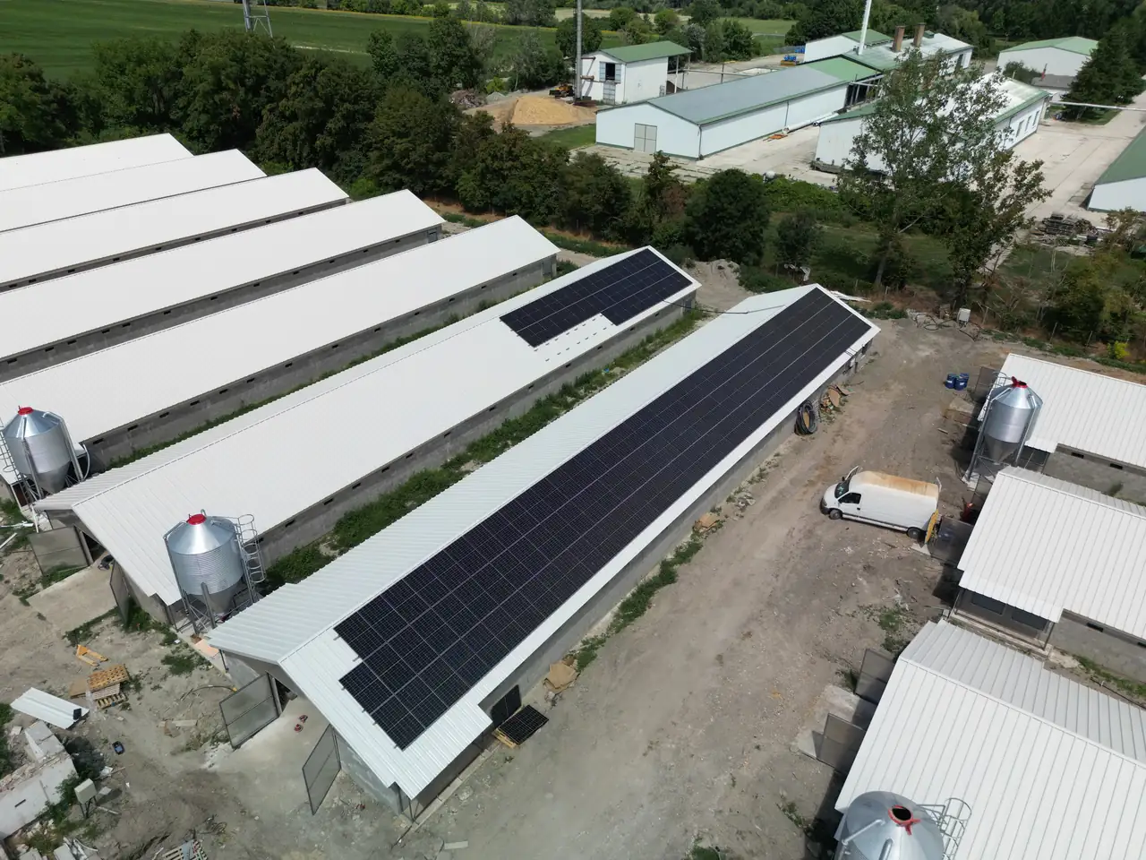 A képen egy napelem telepítés látható, ahol a napelemek a tetőkön helyezkednek el, Szeged városában. Az Ares Solar Construction Kft. által végzett munkálatok során a modern napelemes rendszerek hatékonyan használják ki a napenergiát. A háttérben láthatók a különböző épületek, valamint a telepítési folyamat részeként használt gépek és járművek.