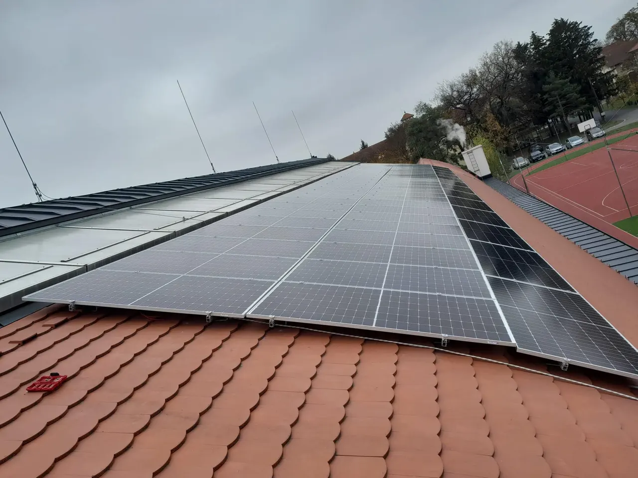 Dócon, az Ares Solar Construction Kft. napelem telepítés szolgáltatásának keretében telepített napelemek láthatók egy tetőn. A képen jól látszanak a fekete színű napelem panelek, amelyek a ház cseréptetőjére vannak rögzítve. Az idő borongós, ami a napelemek karbantartásának fontosságát hangsúlyozza.