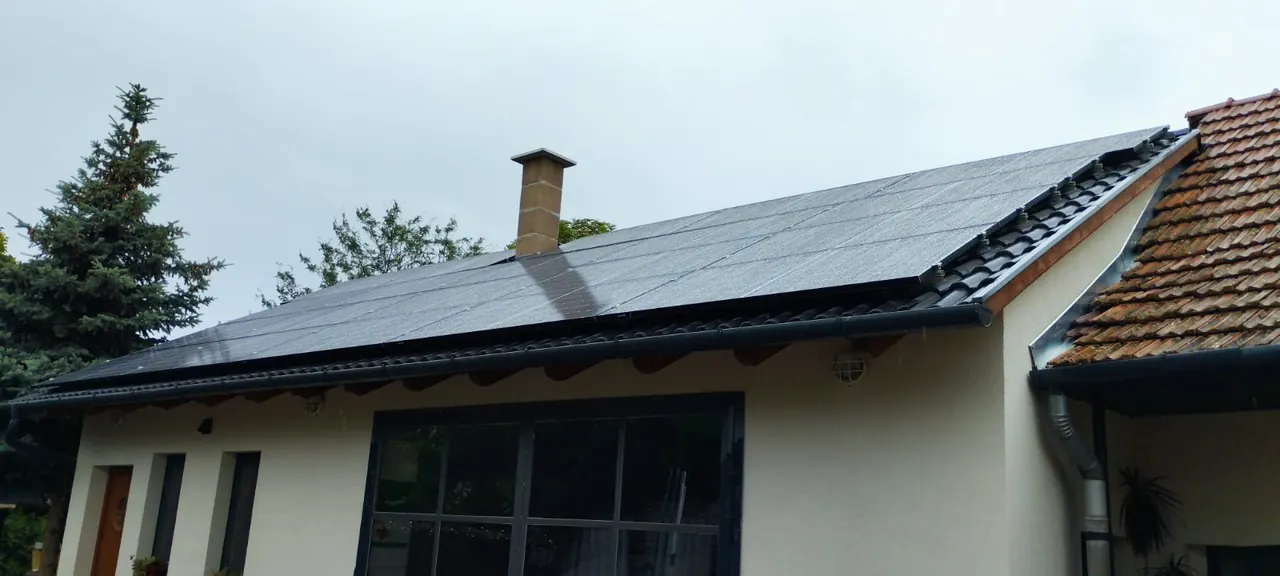 Dócon, az Ares Solar Construction Kft. által végzett napelem telepítés látható egy modern ház tetején. A fekete napelemek szépen integrálódnak a tetőbe, miközben a szürke égbolt hátteret ad a képen. A napelem lízing szolgáltatás lehetősége is említésre méltó, hiszen így a fenntartható energia könnyen elérhetővé válik a helyi lakosok számára.