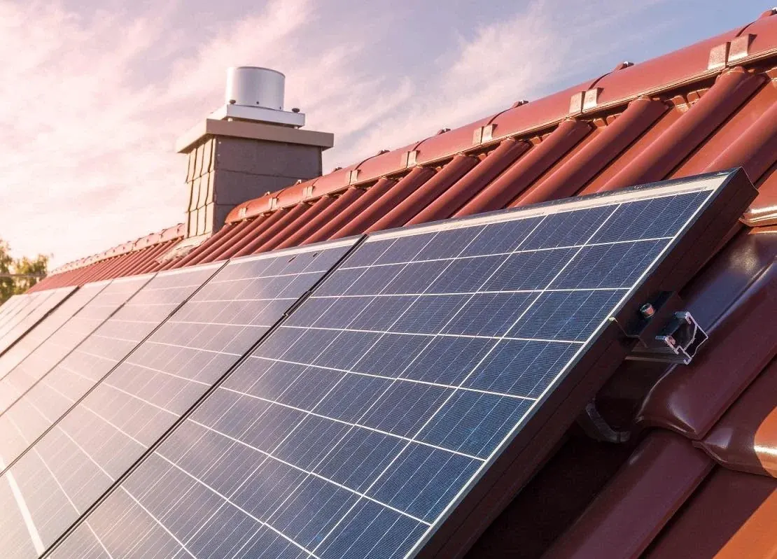 A képen egy háztetőn elhelyezett napelem rendszer látható, amely napfényben csillog. A napelemek az Eger városában működő Ares Solar Construction Kft. napelem telepítési szolgáltatásának részeként lettek telepítve. A tető színével és anyagával harmonizáló napelemek ideális megoldást kínálnak a megújuló energia hasznosítására.