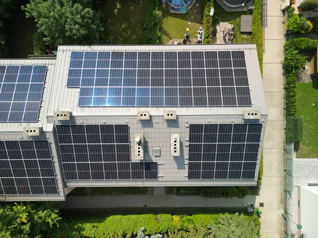 Debrecenben, az Ares Solar Construction Kft. napelem telepítési projektje látható, ahol egy modern ház tetején szépen sorakoznak a napelemek. A képen az épület körüli zöld területek és a rendezett udvar is megjelenik, ami hangsúlyozza a fenntartható energiatermelés fontosságát és a környezetbarát életmódot.