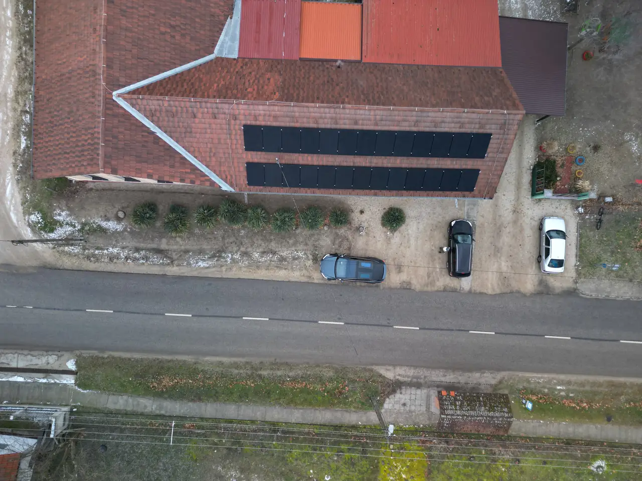 Dóc településén az Ares Solar Construction Kft. által végzett napelem telepítés látható egy ház tetején. Az épület vörös tetővel rendelkezik, és a napkollektorok szépen elhelyezkednek rajta. Az udvarban két autó parkol, és az út mentén zöld fák sorakoznak, amely még inkább kiemeli a környezet szépségét. A képen a napelemek modern megoldásként tűnnek fel a fenntartható energia érdekében.