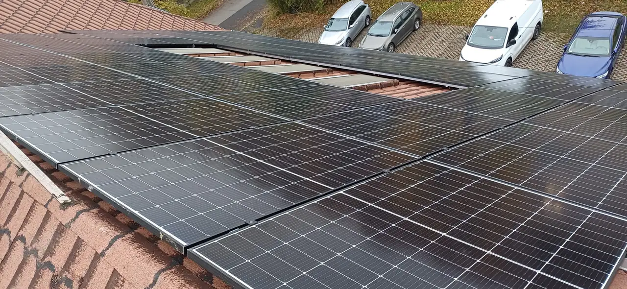 A képen egy Miskolc városában végzett napelem telepítés látható, ahol a tetőre szerelt napelemek sorakoznak. A napelemek fényes felületei jól láthatók, és a háttérben több autó parkol egy rendezett udvarban. Az Ares Solar Construction Kft. szakértelmét tükröző telepítési munka mutatja be a modern megújuló energiaforrások használatának fontosságát.