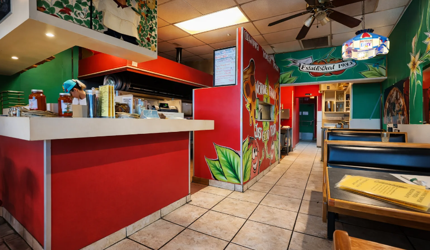 Bright restaurant interior featuring a red counter, green walls with murals, and wooden dining booths