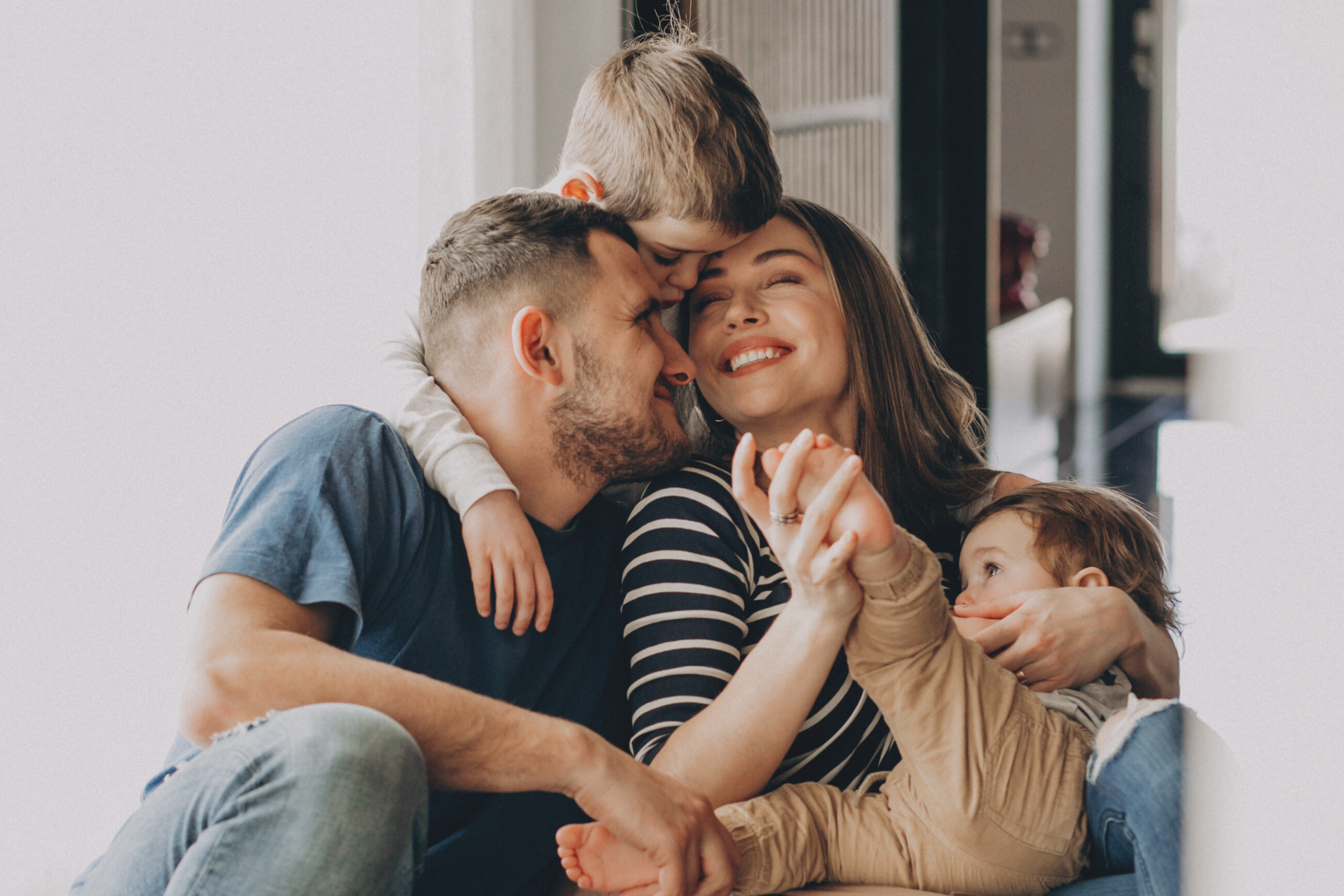 happy parents with two young children holding each other and smiling, confident in their mortgage protection insurance and financial security
