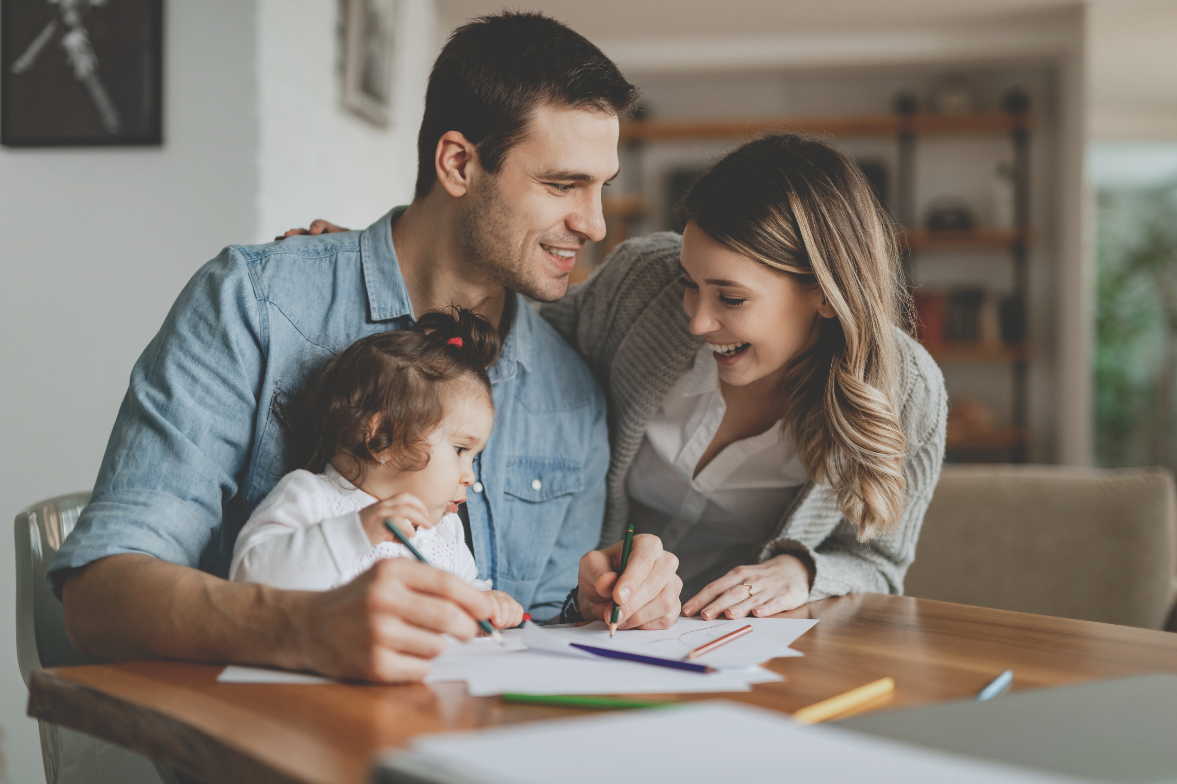 happy young couple with small child reviewing finances, confident in their tax-free retirement and IUL strategy