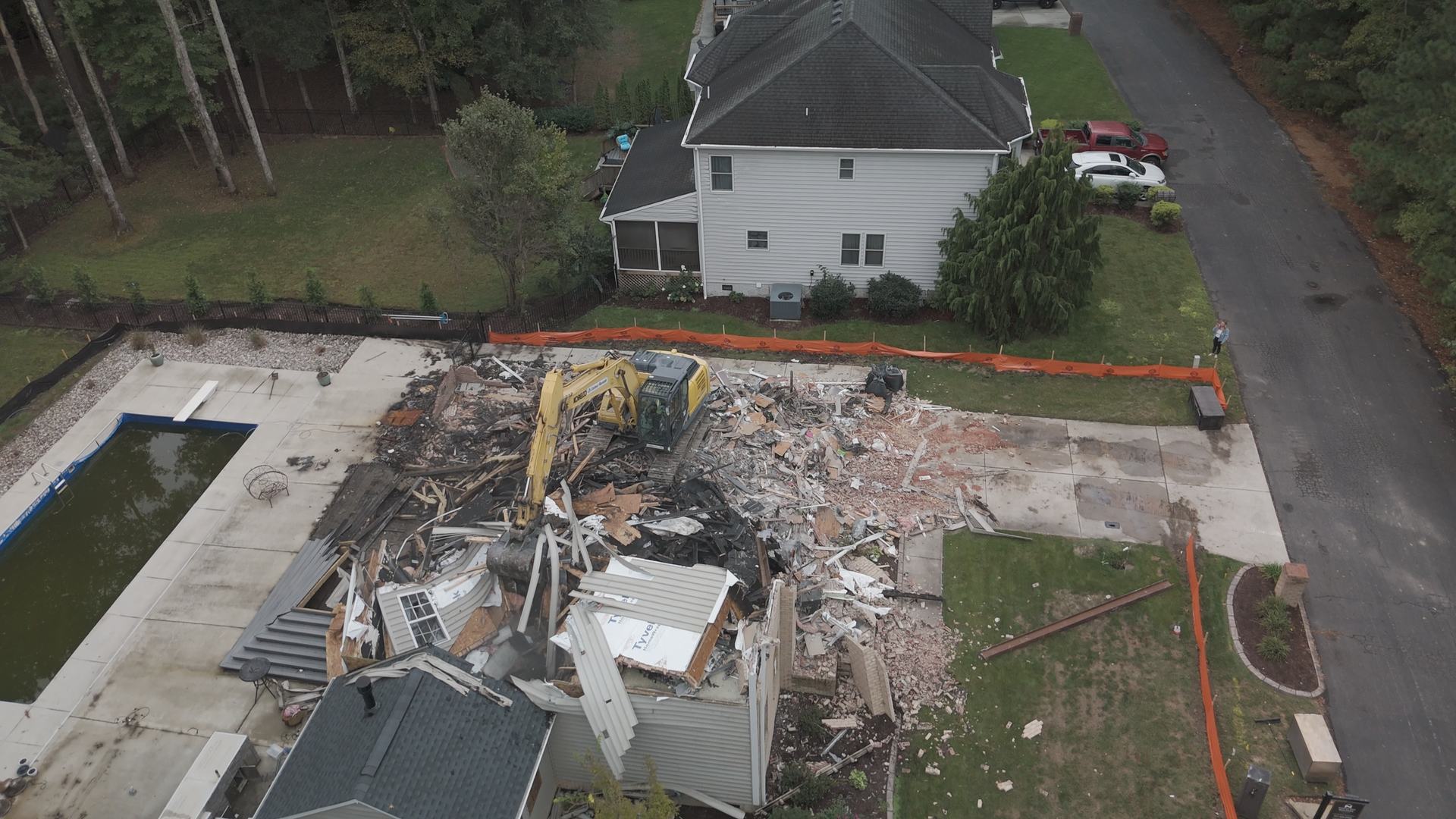 Aerial drone view of a demolition site with an excavator taking down a structure