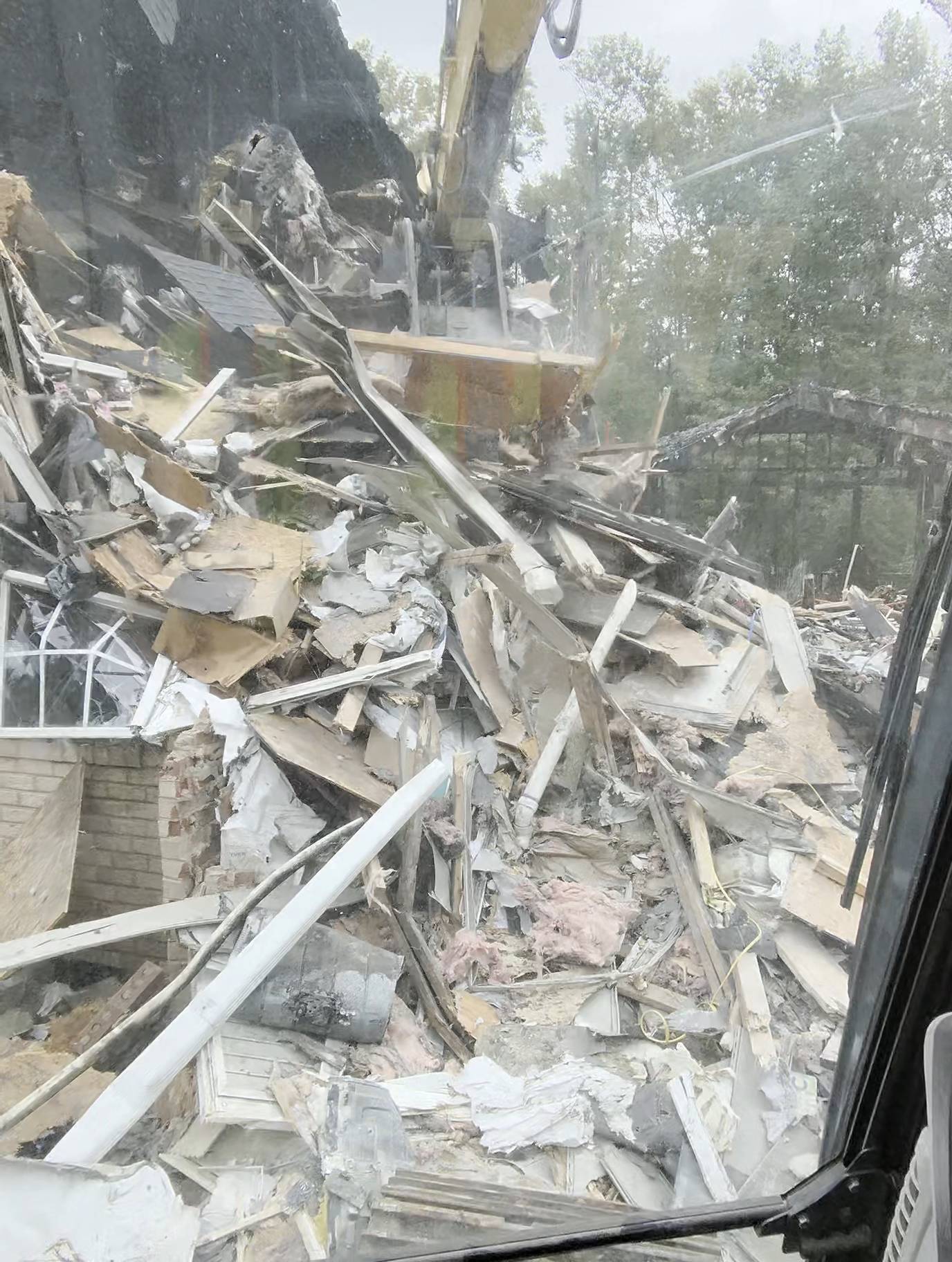 View from the excavator cab onto a demolition debris pile