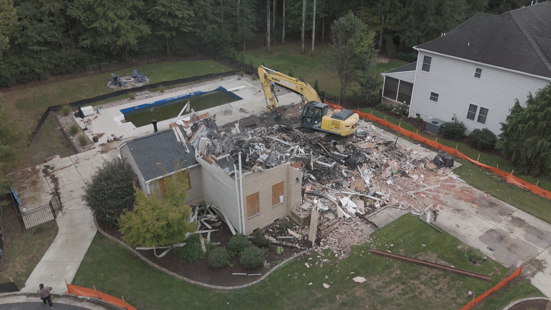 Excavator demolishing a house and clearing the lot