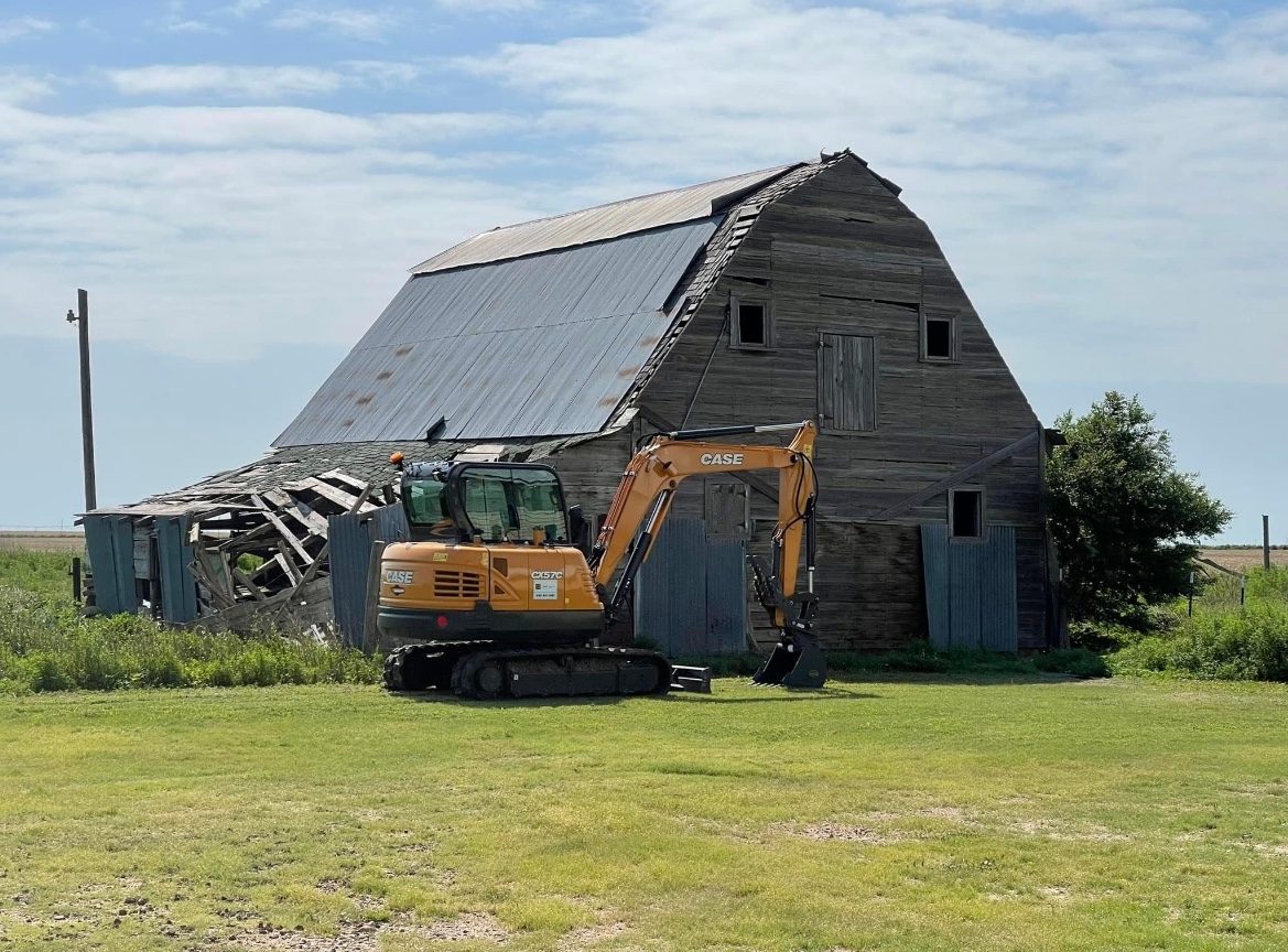 Excavator demolishing barn