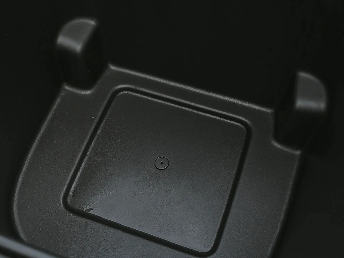 Close-up of the textured, dark gray interior of a plastic storage box with a small circular indentation.