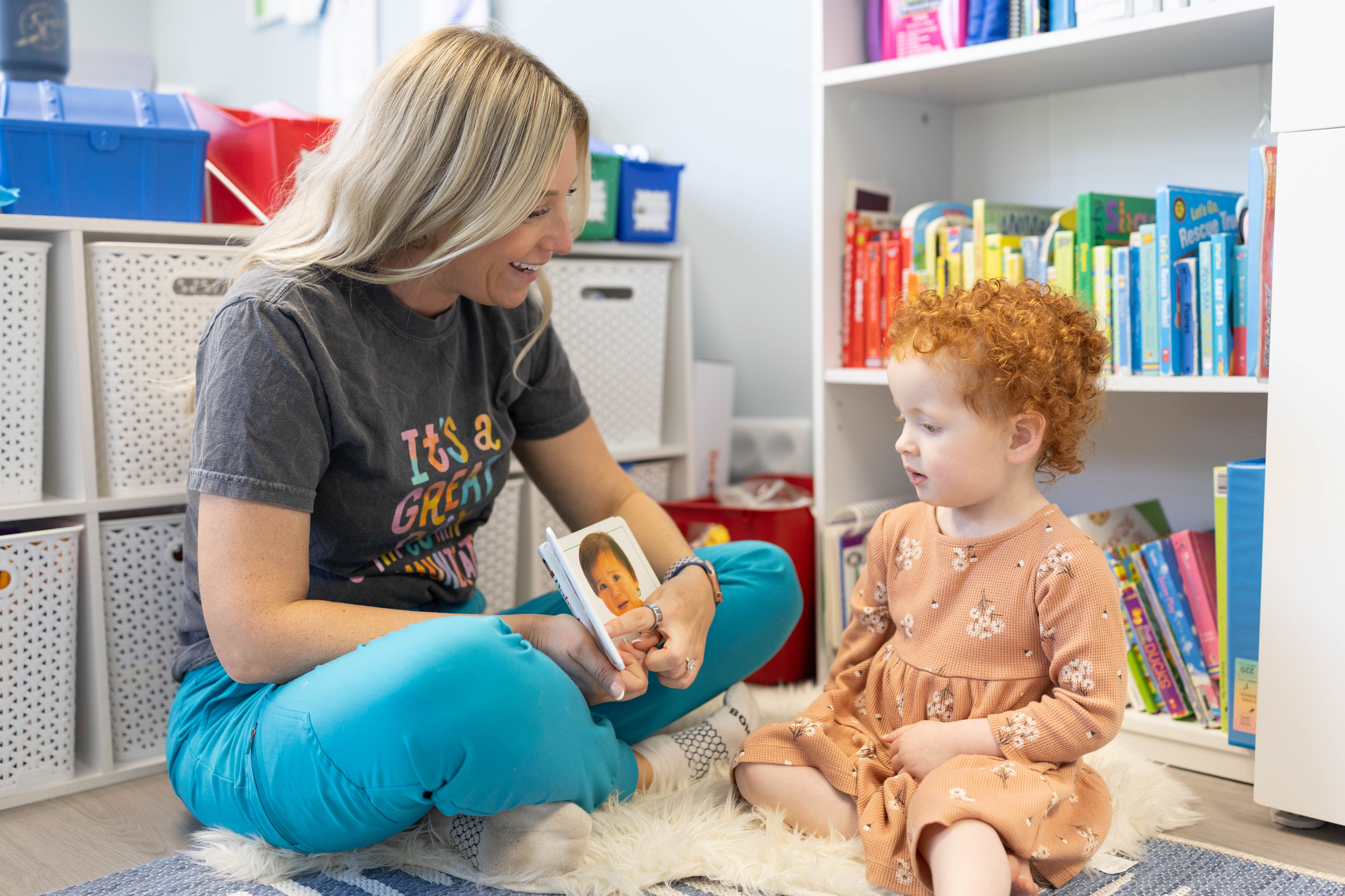 Speech-language pathologist Jillian Lenhard sitting on the floor reading with a young child during a therapy session at The Speech Path SLP in Williamsville, NY